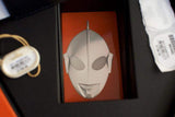 Silver Ultraman mask insert in luxury watch box with orange background and tags