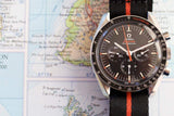 Black chronograph luxury watch with orange stripe nylon strap on a detailed map background