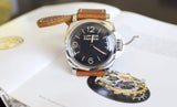 Panerai Luminor wristwatch with brown leather strap and black dial displayed on an open book.