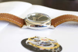 Luxury wristwatch with brown leather strap and polished silver case on an open book