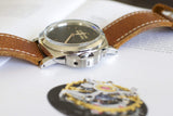 Luxury Swiss watch with brown leather strap and black dial on open book