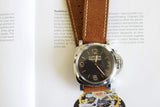 Panerai Luminor luxury watch with brown leather strap on an open book background