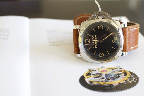 Luxury Panerai Luminor watch with brown leather strap displayed on an open book