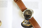 Luxury Panerai wristwatch with brown leather strap on open magazine