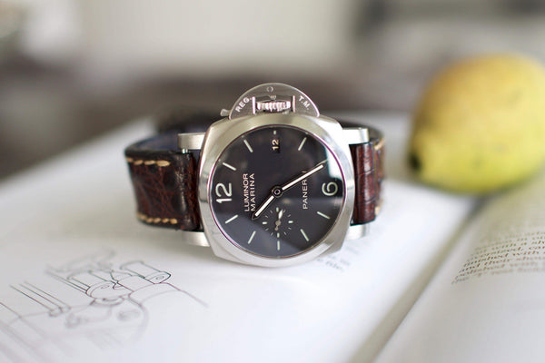 Luxury Swiss watch with black dial and brown leather strap resting on open book