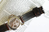Close-up of a Panerai luxury watch with visible movement and leather strap on book background