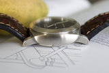 Swiss luxury watch with brushed metal case and brown leather strap on technical drawing