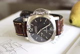 Luxury Panerai Luminor Marina watch with black dial and brown leather strap on open book