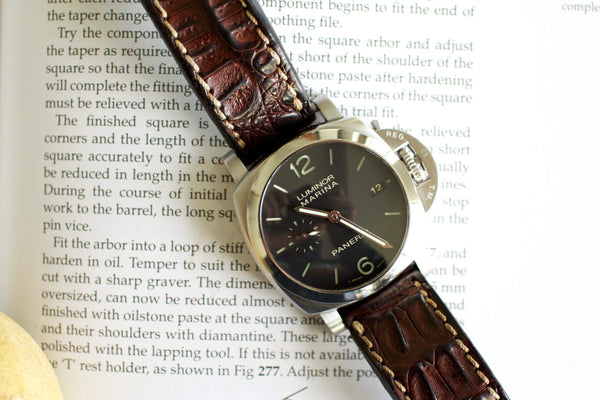 Luxury Luminor Marina watch with brown leather strap placed on an open book
