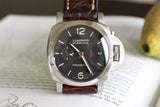 Luxury Swiss watch with black dial, brown leather strap, stainless steel case on book