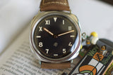 Luxury Swiss watch with black dial, mixed numerals, tan leather strap, close-up shot