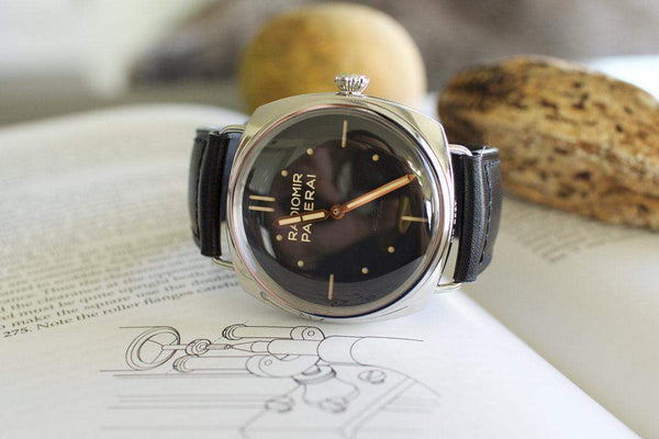 Panerai Radiomir luxury wristwatch with black leather strap on an open book