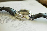Luxury Swiss-made wristwatch with black leather strap resting on an open book