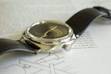 Luxury black leather wristwatch with silver case placed on an open instruction manual