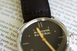 Close-up of a Panerai Radiomir luxury watch with black leather strap on an open book