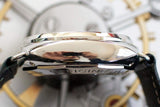 Side view of a luxury watch with polished stainless steel case and black leather strap