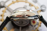 Close-up side view of a polished luxury watch case and crown with a leather strap