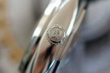 Close-up of a luxury watch crown with brushed stainless steel finish and engraved logo