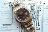 Rolex Datejust luxury watch with diamond markers on a technical watch blueprint background