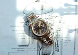 Silver Rolex Datejust luxury watch resting on a vintage clock technical diagram.