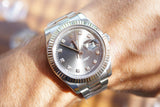 Close-up of a Rolex Datejust luxury watch with diamond markers on a person's wrist.