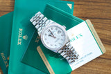 Rolex Datejust watch with diamond bezel and mother-of-pearl dial on green luxury packaging