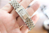 Close-up of a stainless steel Rolex jubilee bracelet clasp held in a hand