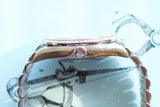 Side view of a luxury silver watch with a diamond-set bezel and crown.
