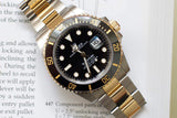 Two-tone gold and steel Rolex Submariner Date luxury watch resting on a technical document.