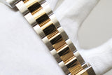Close-up of a two-tone gold and silver luxury watch bracelet on a white gloved hand.