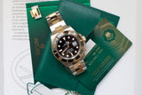 Rolex Submariner Date luxury watch with gold and steel bracelet and green presentation box.
