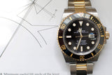 Two-tone Rolex Submariner luxury watch with black dial and gold accents on technical drawings