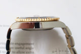 Close-up side view of a luxury gold and black bezel watch with a silver stainless steel band.