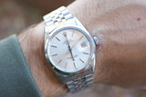 Close-up of a vintage Rolex Oyster Perpetual Date watch with a silver jubilee bracelet on a wrist.