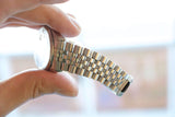 Close-up of a person holding a luxury Swiss-made watch with a silver stainless steel link bracelet