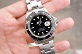Close-up of a Rolex Submariner luxury watch with a black dial and silver stainless steel band.