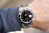 Close-up of a Rolex Submariner luxury watch with a black dial on a man's wrist.