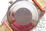 Close-up of a luxury watch case back with a brown leather strap