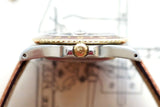 Side view of a luxury gold and steel watch with a brown leather strap