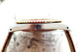 Side view of a luxury gold and silver watch with a brown leather strap