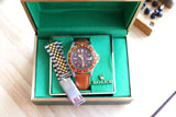 Rolex GMT-Master watch with brown leather strap and two-tone metal bracelet in a green box