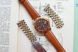 Rolex luxury watch with brown dial and bezel, brown leather strap, and two metal bracelets