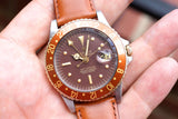 Rolex GMT-Master luxury watch with brown bezel and leather strap held in hand
