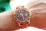 Rolex GMT-Master watch with a brown bezel and brown leather strap on a wrist