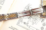 Close-up of a two-tone stainless steel and gold Rolex watch bracelet on a technical drawing.