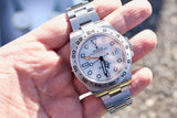 Close-up of a Rolex Explorer II luxury watch with white dial and steel bracelet held in a hand.
