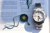 Rolex Oyster Perpetual Date luxury watch with green seal on descriptive text document