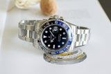 Stainless steel luxury GMT watch with blue and black bezel on open book