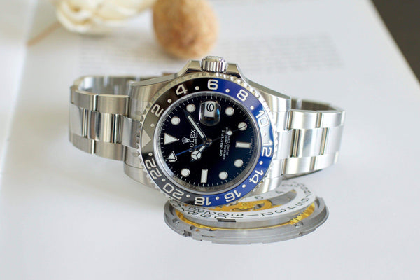 Stainless steel luxury GMT watch with blue and black bezel on open book