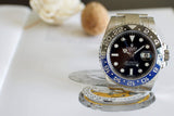 Luxury stainless steel GMT watch with black and blue bezel on white background, close-up.